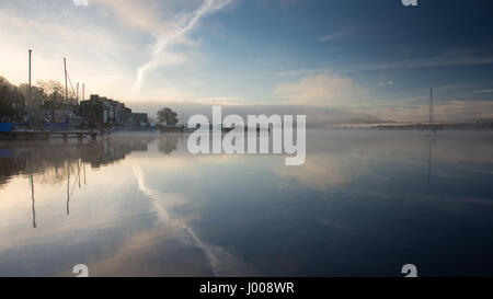 La brume s'élève de ses eaux calmes du lac Windermere, à l'embarcadère, à côté de Waterhead Ambleside Youth Hostel, en Angleterre du Lake District National Park. Banque D'Images