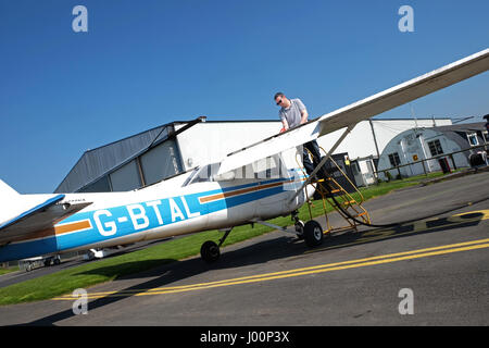 L'aérodrome de Shobdon, Herefordshire, UK - Avril 2017 - Perfect chaude journée ensoleillée à l'aérodrome de Shobdon avec un ciel bleu parfait pour l'Herefordshire Aero Club. Un pilote ravitaille son Cessna 152 prêt pour un vol local. Banque D'Images