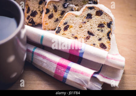 Stollen de Noël allemand traditionnel, gâteau aux raisins levure servi avec une tasse de café, décoré de la nappe sur une table en bois, selective focus Banque D'Images