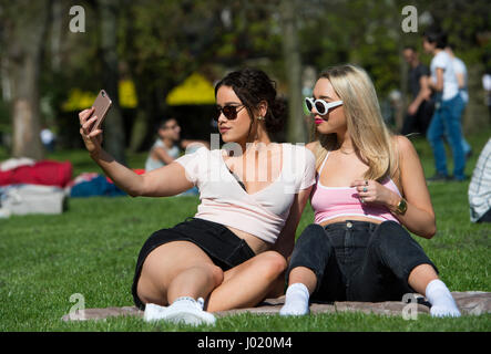 Jessica Summers (à gauche) et Ellie Ford prendre un bain de soleil tout en selfies à Hyde Park, Londres, comme vacances de Pâques au printemps, les températures estivales ce week-end à des hauteurs que la journée la plus chaude de l'année devrait arriver sur les côtes britanniques. Banque D'Images