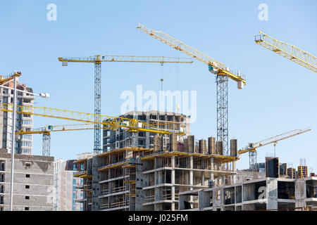 Unfinished building construction and building cranes against clear blue sky background Banque D'Images