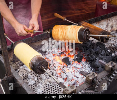 Kurtos kalacs ou gâteaux de cheminée roll spinning sur des charbons ardents à un stand de marché,le sucré typique de Budapest, Hongrie Banque D'Images