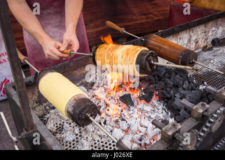 Kurtos kalacs ou gâteaux de cheminée roll spinning sur des charbons ardents à un stand de marché,le sucré typique de Budapest, Hongrie Banque D'Images