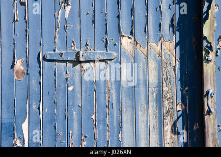 Shabby ensembles de garage ou portes en bois en usine avec l'épluchage et la peinture bleu délavé avec colonnes en brique rouge et blanc sur un bâtiment vide à Avonmouth Banque D'Images