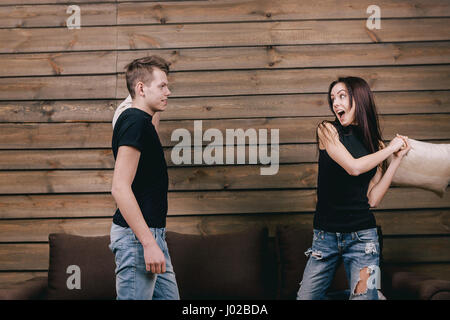 Heureux couple body glamour à la maison. Ils portent en chemise noire et un jean et se tenir sur bendend les genoux sur le lit. Tout le monde est maintenant un oreiller Banque D'Images