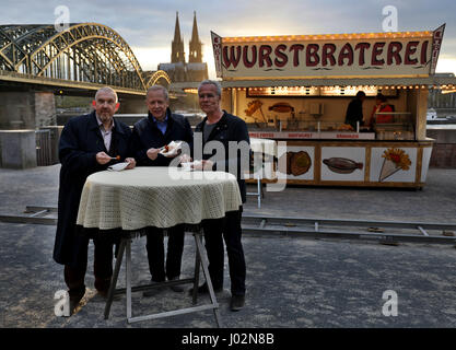 Cologne, Allemagne. 6ème apr 2017. Klaus acteurs Behrendt (R) et Dietmar Baer, de commissaires du Max Ballauf et Freddy Shenk dans l'émission de télévision allemande Tatort's édition de Cologne, et de radiodiffuseur public du WDR directeur Tom Buhrow (C) s'élèvent à une table à l'extérieur d'un décrochage de la saucisse utilisée dans la série à Cologne, Allemagne, 6 avril 2017. L'épisode suivant sera son 71e. Photo : Oliver Berg/dpa/Alamy Live News Banque D'Images