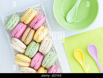 Assortiment de macarons aux couleurs de l'été assez disposer dans un bac délicate avec une serviette de couleur vert lime et cuillères. l'image est verticale et a Banque D'Images