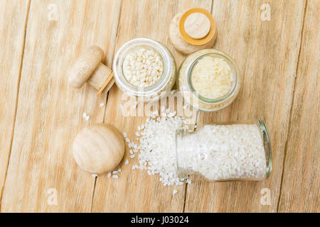 Trois sortes de riz non cuit dans des bocaux en verre sur une table en bois Banque D'Images