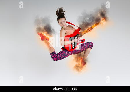 Femme dans les sauts avec une guitare dans le studio Banque D'Images