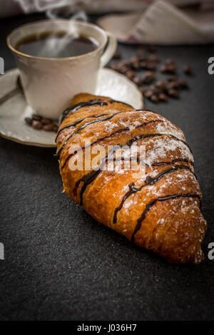 Petit-déjeuner traditionnel français croissant avec du chocolat et du café sur la table en pierre noire Banque D'Images