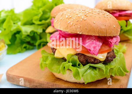 Des hamburgers avec escalope, juteux, tomates et concombres choucroute, fromage, laitue verte et un bun au sésame Banque D'Images