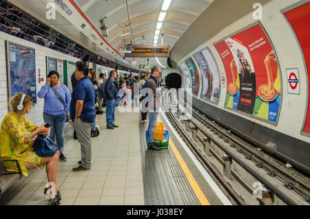 Passagers attendent sur la plate-forme à la station de métro Shepherds Bush pour un train sur la ligne centrale. Banque D'Images