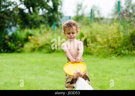 Garçon avec drôle de visage expression et langue Playing with dog Banque D'Images
