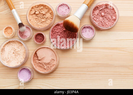 Poudre maquillage produits avec les pinceaux sur fond de bois Banque D'Images