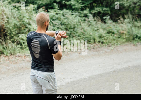 Vue arrière d'un coureur debout sur un sentier nature contrôle de temps Banque D'Images