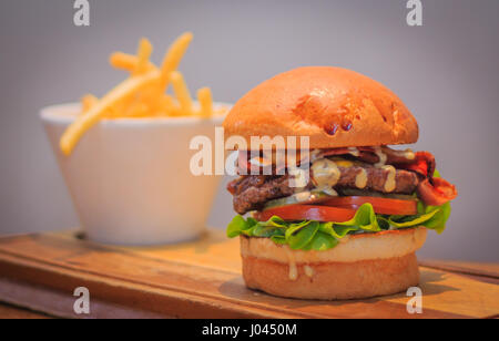 Poitrine de boeuf américain burger avec sauce spéciale, chêne laitue, tomate, cornichon, bacon, fromage, lait pain et frites. Banque D'Images