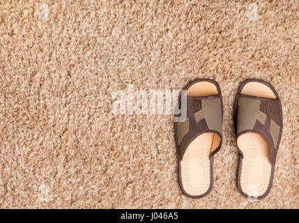 Chaussons en cuir pour hommes debout sur le bord d'un tapis laineux Banque D'Images