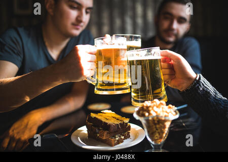 Les gens, les hommes, les loisirs, l'amitié et de fête concept - heureux amis boire une bière et clinking glasses au bar ou au pub Banque D'Images