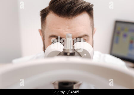 Examen de la vue. Nice professionnel agréable ophtalmologiste à jumelles spécial en vue de l'essai et en faisant son job Banque D'Images