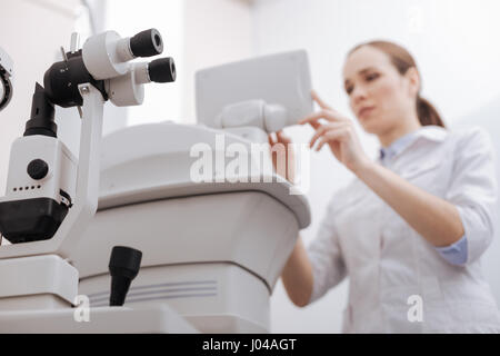 Belle femme agréable de travailler avec l'équipement d'essai de l'œil Banque D'Images