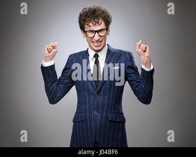 Super drôle excité le génie du mal d'affaires. Acteur professionnel de l'expression du visage. Souriant à pleines dents, serrant les poings. Banque D'Images