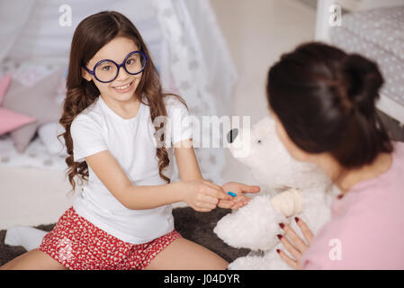 Charmante petite fille en prenant soin de ses jouets préférés à la maison Banque D'Images