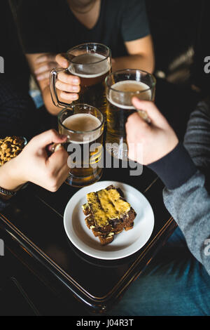 Les gens, les loisirs et les boissons concept - close up of male hands tintement des verres à bière et des bretzels au bar ou au pub Banque D'Images