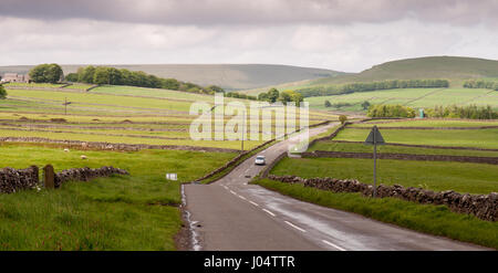 Une route serpente à travers les champs marqués avec des murs en pierre sèche en Angleterre's Peak District. Banque D'Images