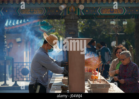 L'homme met de l'Encens au Temple de Wong Tai Sin, Hong Kong. Banque D'Images