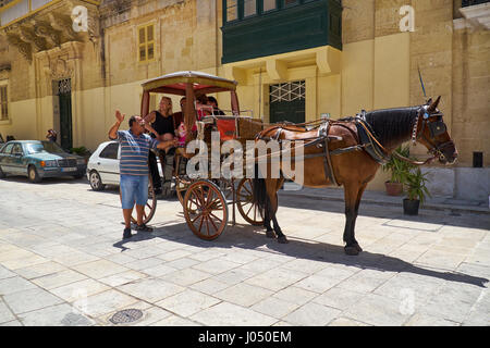 MDINA, MALTE - Juillet 29, 2015 : La course donne une visite guidée pour les touristes assis dans la calèche sur le St Paul's Square, Mdina, Malte. Banque D'Images