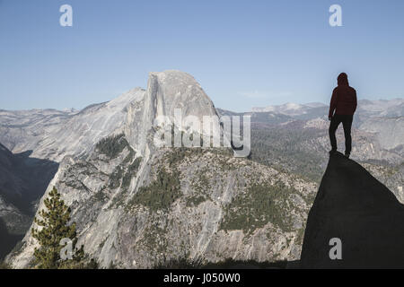 Un jeune randonneur est debout sur un rocher en profitant de la vue vers la fameuse Demi Dôme à Glacier Point au coucher du soleil, Yosemite National Park, California, USA Banque D'Images