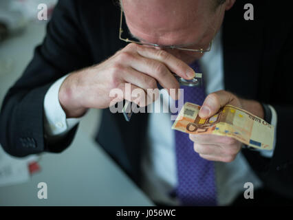 Mainz, Allemagne. 30Th Mar, 2017. Rainer l'orme, le chef du centre d'analyse de la contrefaçon de la banque fédérale allemande inspecte les deux 50 euro note avec un magnyfying glass à Mainz, Allemagne, 30 mars 2017. La Banque fédérale allemande a un centre de l'analyse de la contrefaçon qui est situé au siège de l'institution, à Mayence. Photo : Andreas Arnold/dpa/Alamy Live News Banque D'Images