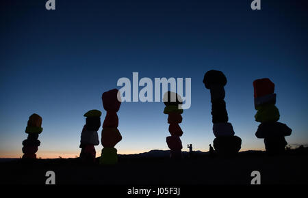 Jean, Nevada, USA. 10 avr, 2017. Photographie les gens au coucher du soleil l'art public à grande échelle installation intitulée sept Montagne magique" par l'artiste suisse Ugo Rondinone April 10, 2017 près de Jean, Nevada. L'œuvre, composée de sept tours de couleurs, de rochers empilés debout plus de trente pieds de haut, est programmé pour être affiché jusqu'en mai 2018. Crédit : David Becker/ZUMA/Alamy Fil Live News Banque D'Images