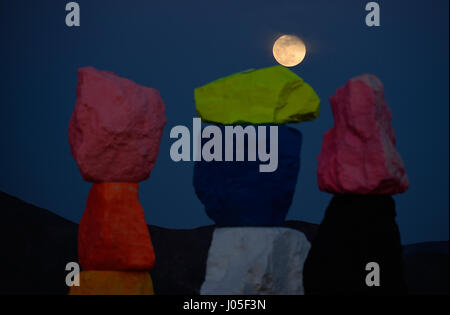 Jean, Nevada, USA. 10 avr, 2017. La pleine lune se lève sur l'art public à grande échelle installation intitulée sept Montagne magique" par l'artiste suisse Ugo Rondinone April 10, 2017 près de Jean, Nevada. L'œuvre, composée de sept tours de couleurs, de rochers empilés debout plus de trente pieds de haut, est programmé pour être affiché jusqu'en mai 2018. Crédit : David Becker/ZUMA/Alamy Fil Live News Banque D'Images