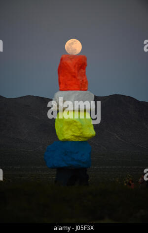 Jean, Nevada, USA. 10 avr, 2017. La pleine lune se lève sur l'art public à grande échelle installation intitulée sept Montagne magique" par l'artiste suisse Ugo Rondinone April 10, 2017 près de Jean, Nevada. L'œuvre, composée de sept tours de couleurs, de rochers empilés debout plus de trente pieds de haut, est programmé pour être affiché jusqu'en mai 2018. Crédit : David Becker/ZUMA/Alamy Fil Live News Banque D'Images