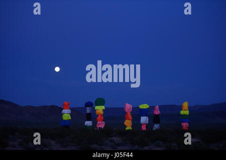 Jean, Nevada, USA. 10 avr, 2017. La pleine lune se lève sur l'art public à grande échelle installation intitulée sept Montagne magique" par l'artiste suisse Ugo Rondinone April 10, 2017 près de Jean, Nevada. L'œuvre, composée de sept tours de couleurs, de rochers empilés debout plus de trente pieds de haut, est programmé pour être affiché jusqu'en mai 2018. Crédit : David Becker/ZUMA/Alamy Fil Live News Banque D'Images