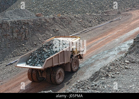 Camion dumper avec pierres chargées en conduisant le long d'une carrière. industrie minière. Banque D'Images