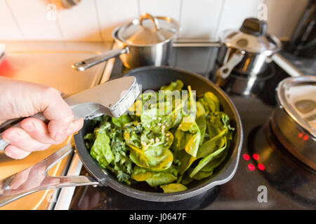 Close up ou de l'ail pressé dans poêle remplie de chou vert et les épinards modèle libération : Oui. Biens : Non. Banque D'Images