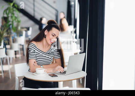 Image of woman using laptop while sitting at cafe. Jeune femme assise dans un café et parler avec vos amis grâce à l'internet. Banque D'Images