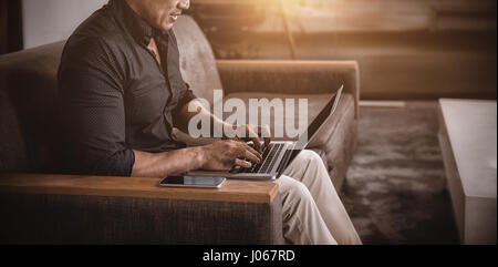 Businessman using laptop while sitting on sofa Banque D'Images