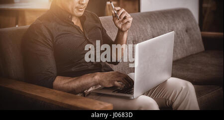 Business executive sitting on sofa using laptop Banque D'Images