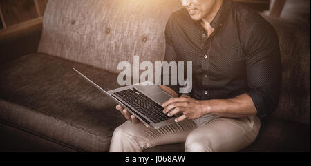 Entrepreneur sitting on sofa using laptop Banque D'Images