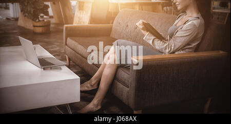 Femme business executive using digital tablet while sitting on sofa Banque D'Images