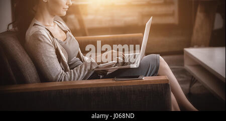 Businesswoman using laptop while sitting on sofa Banque D'Images