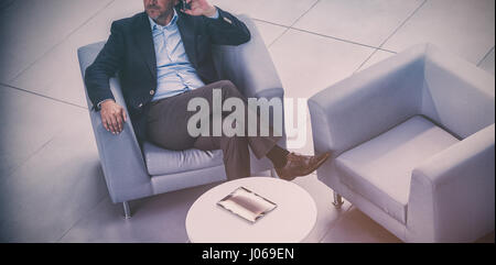 Businessman sitting on chair et talking on mobile phone in office Banque D'Images