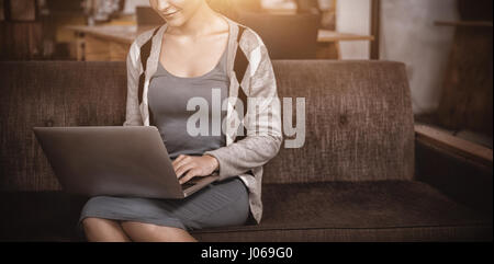 Femme d'affaires en utilisant laptop while sitting on sofa Banque D'Images