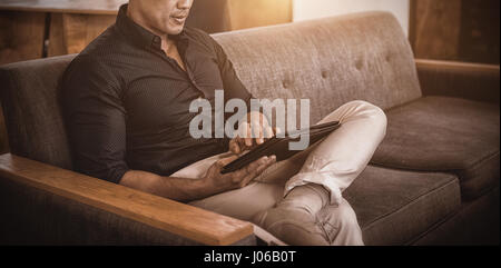 Business executive sitting on sofa using digital tablet Banque D'Images