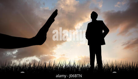 Toute la longueur du businessman with hands on hips contre orange et bleu ciel avec des nuages Banque D'Images