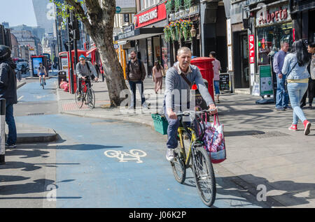 Un homme sur un vélo bas cycles une voie cyclable sur le côté de Whitechapel High Street à Londres. Banque D'Images