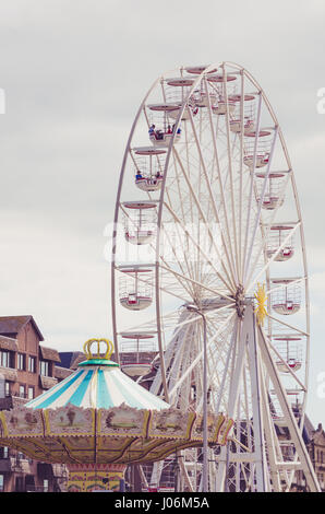 Grande roue sur fond de ciel gris, merry go round en premier plan. Banque D'Images